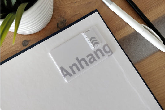 Eine Bachelorarbeit mit eingeklebtem USB-Stick als digitaler Anhang liegt auf einem Schreibtisch.